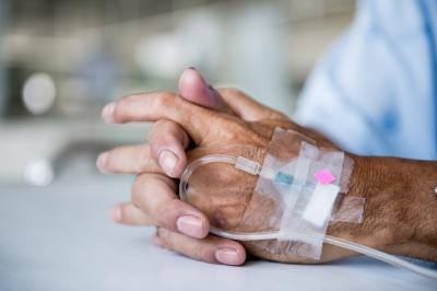 photo of an older man's hand with an IV fluid attached.