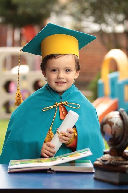 A small boy in a graduation cap and gown holding a diploma - will he go to college?