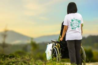 photo of young woman pushing a wheelchair outside