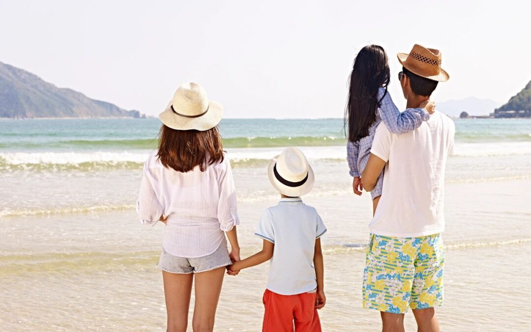 A family of four standing on a beach looking at the horizon.